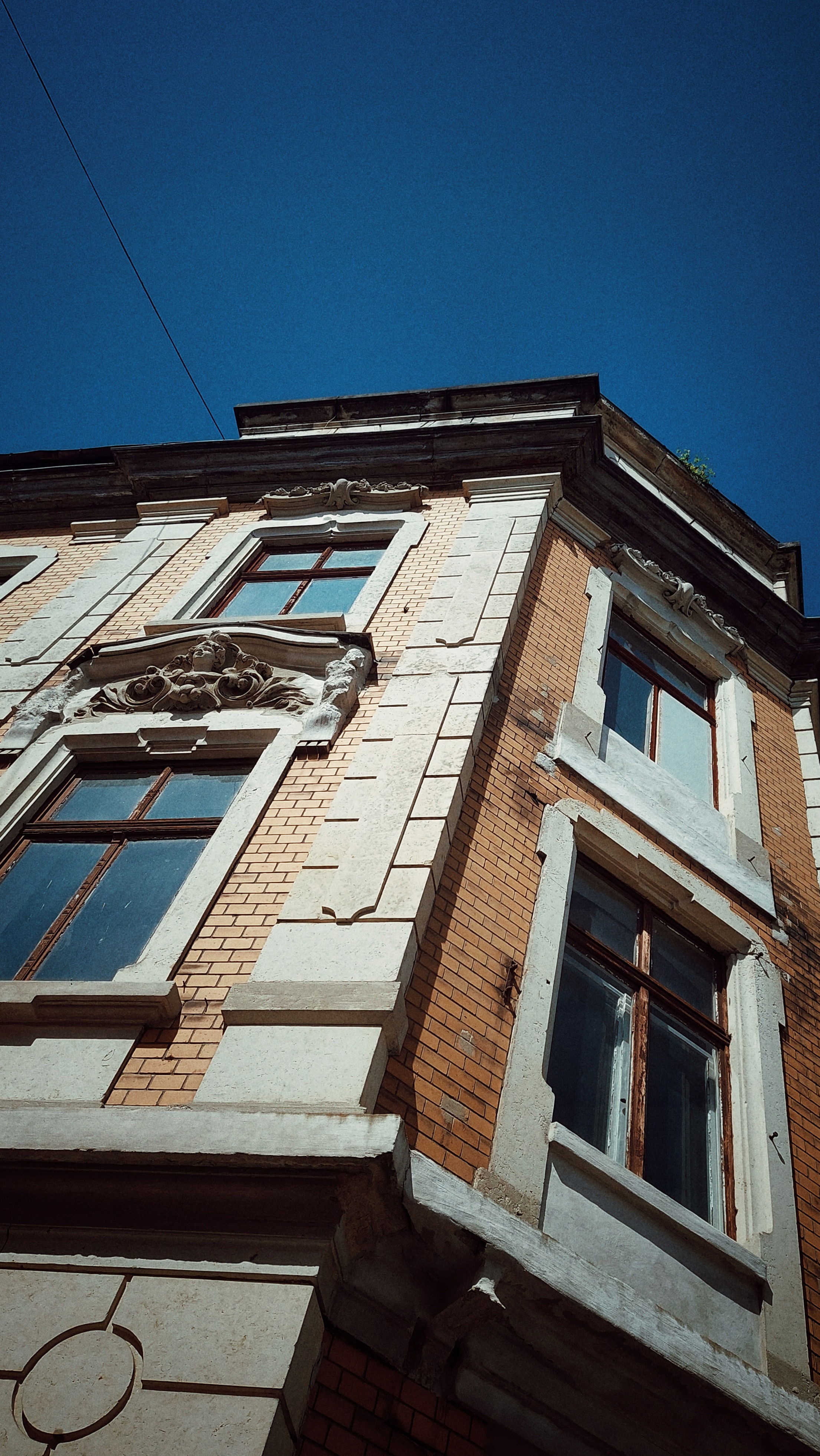 An old houses facade in front of blue sky.