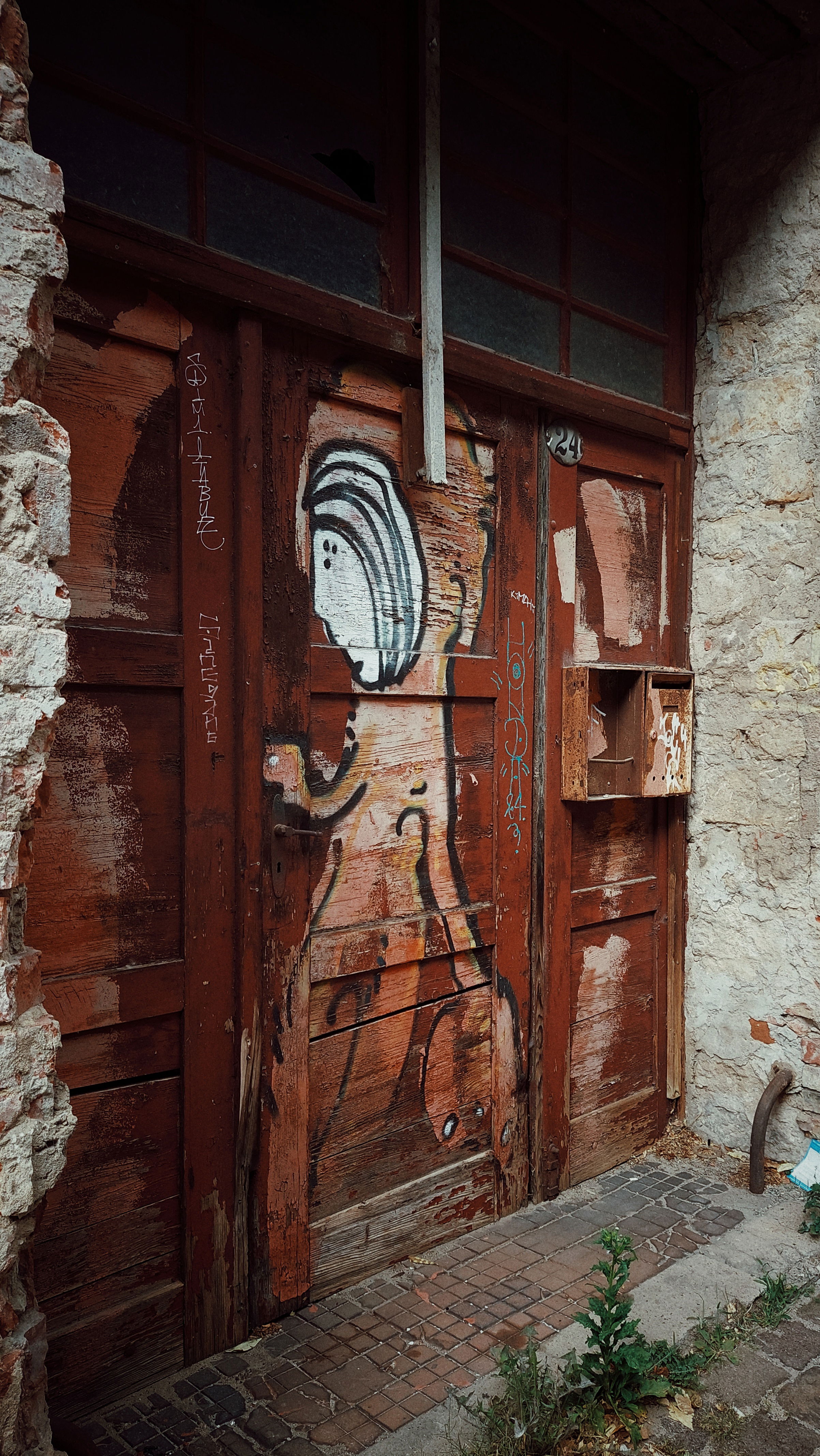 Door of an abandoned house. Streetart, s stylized human being.