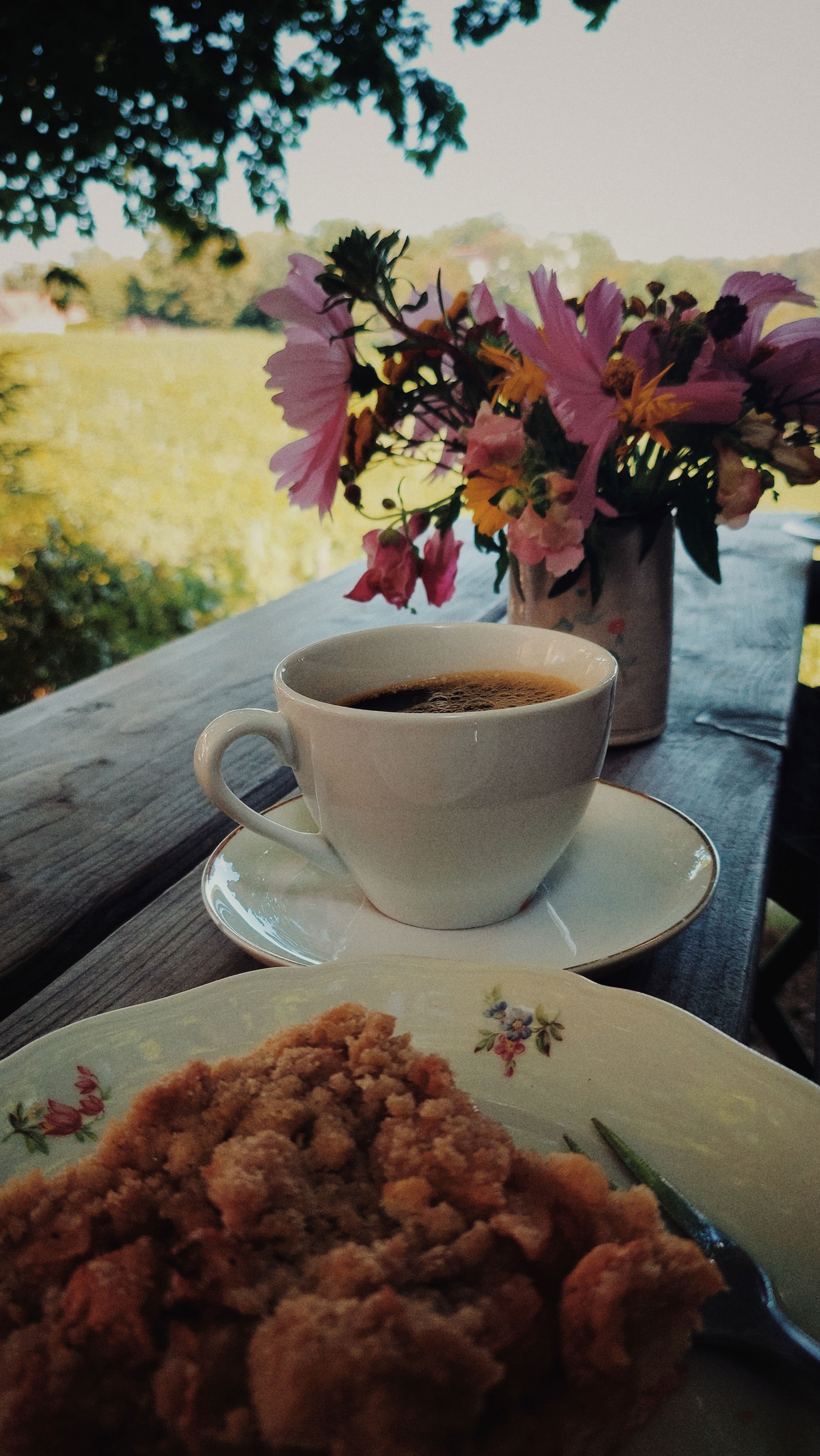 Apple pie, coffee and a bouquet of flowers on a wooden table. 