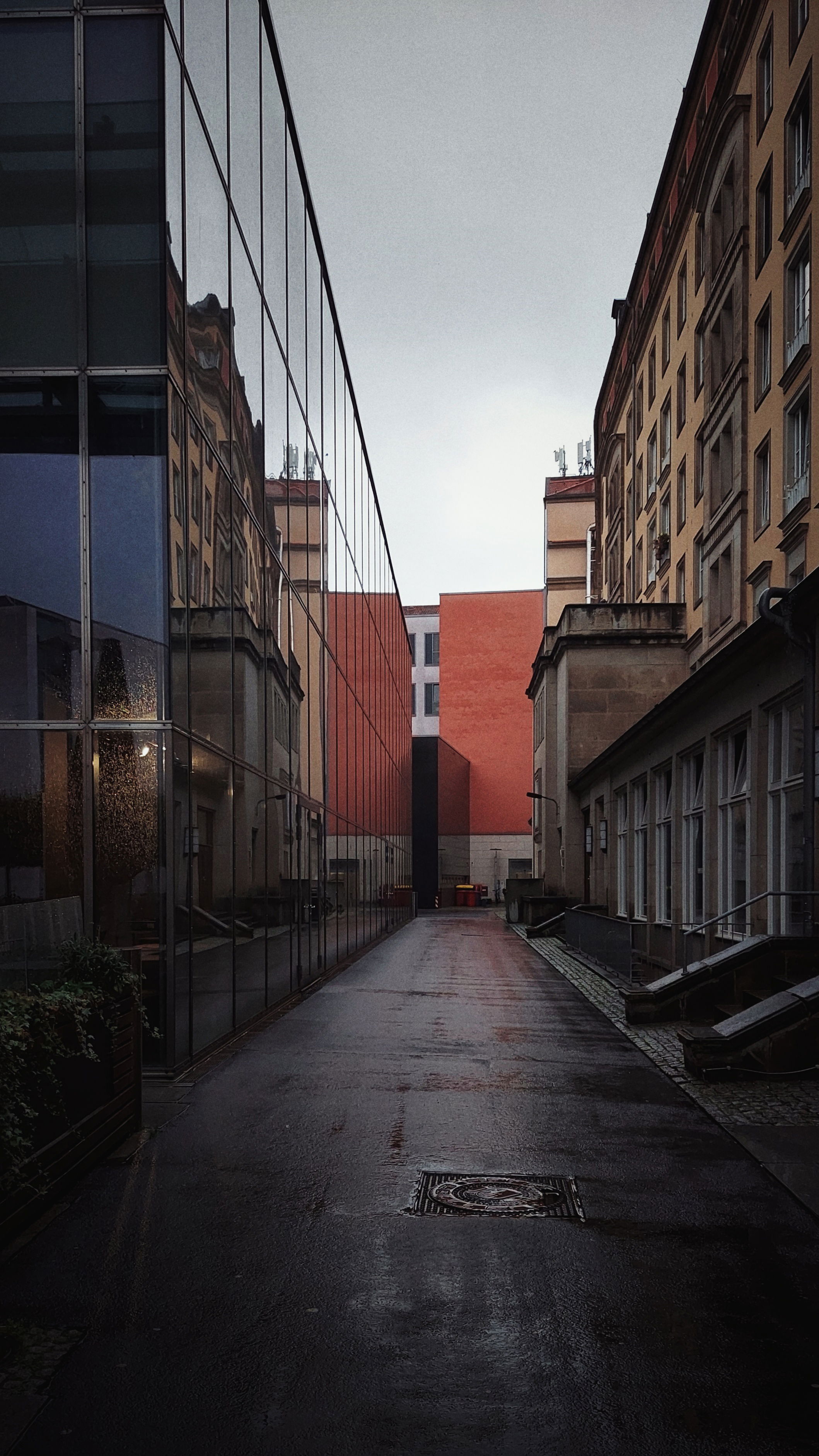 Looking down a narrow road. Modern architecture on the left, old architecture on the right. Rainy autumn mood.