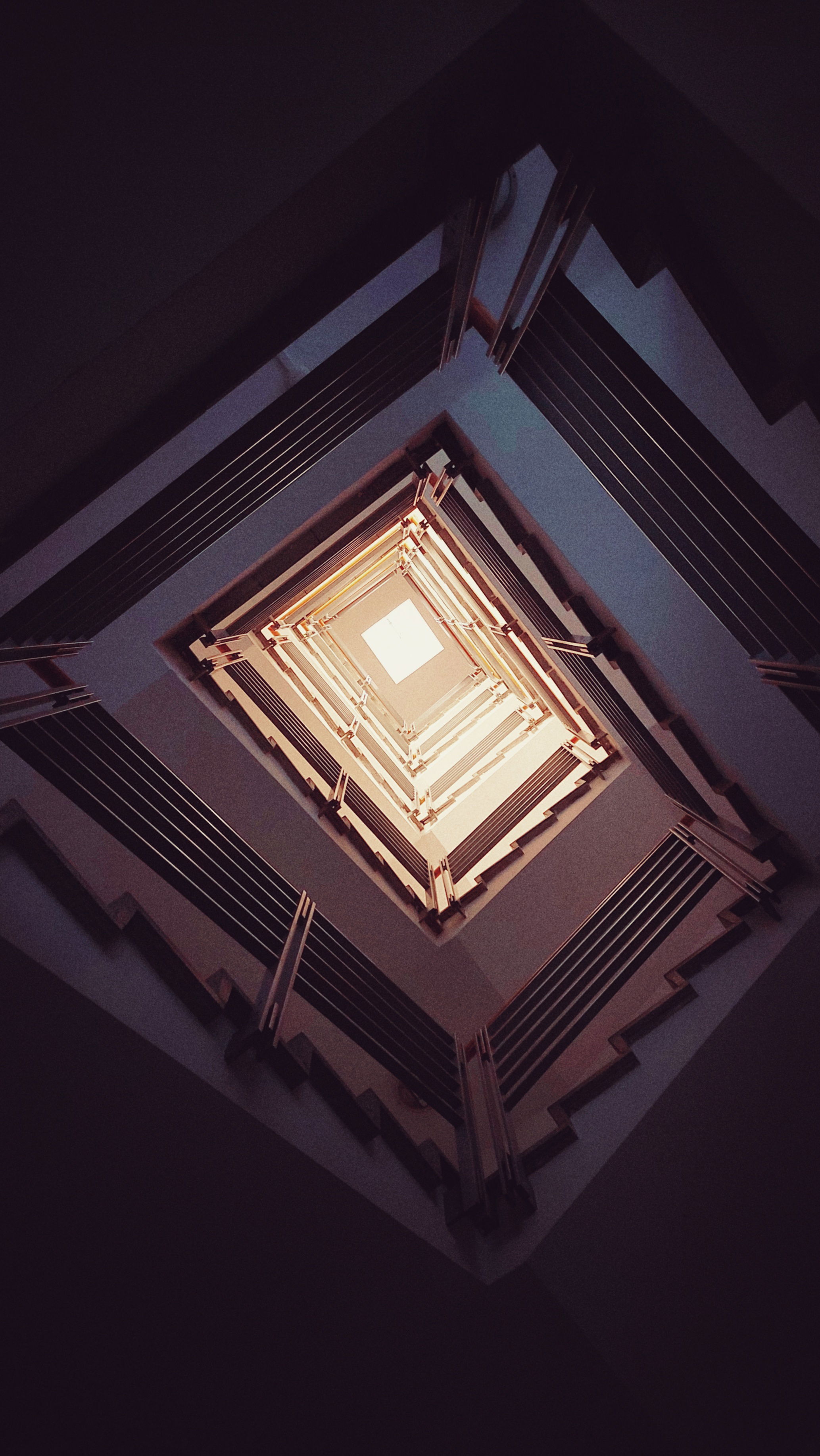 Looking up a contemporary staircase. A window on top.
