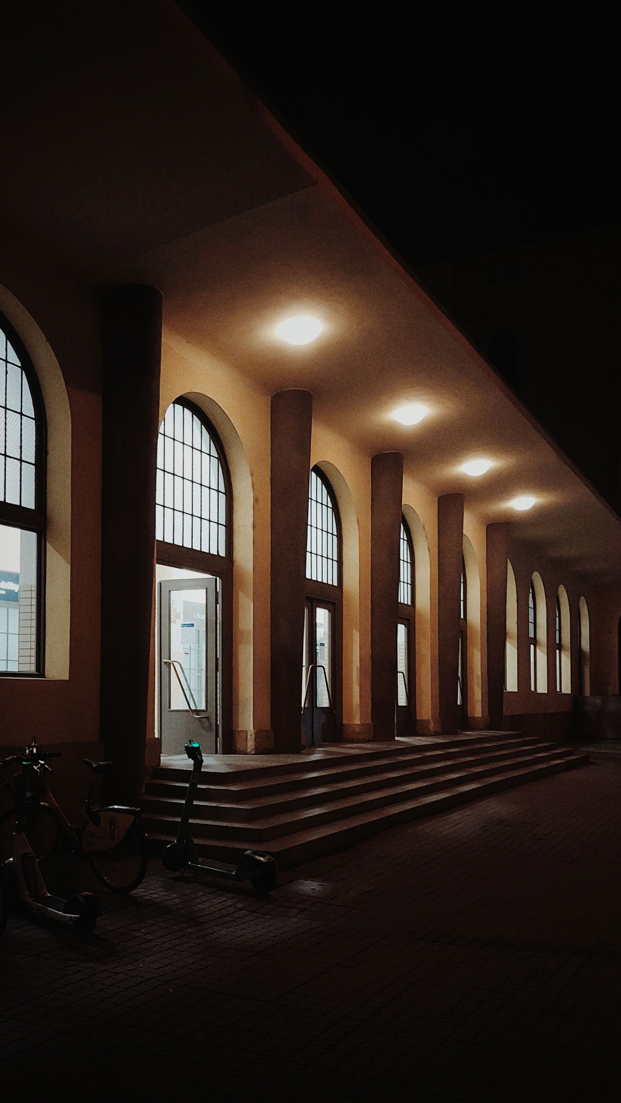 An empty staircase into a railroad station. Four lights above.