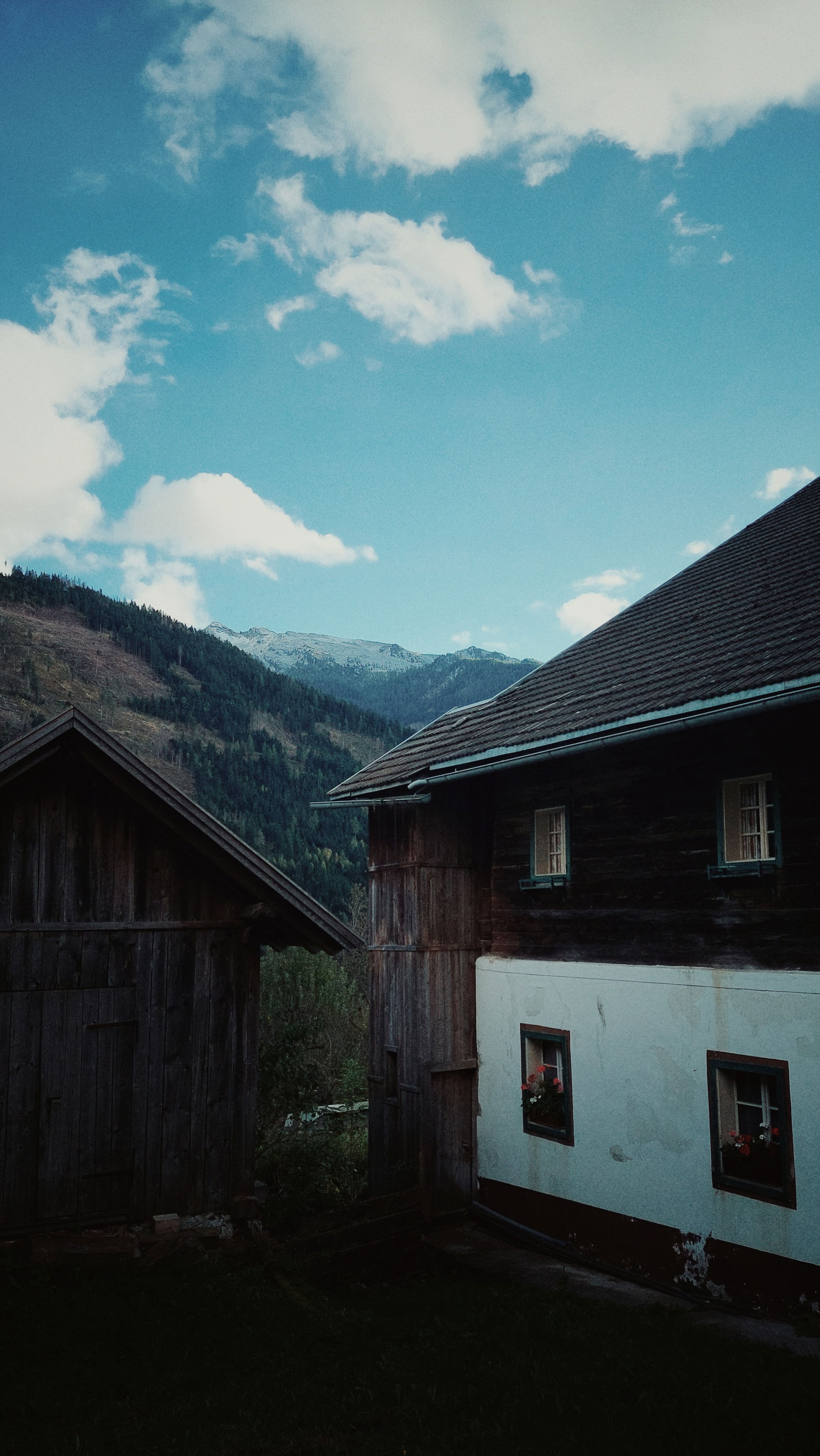 An old mountain home, in a particularly good shape but abandoned. Mountains and blue sky behind. 