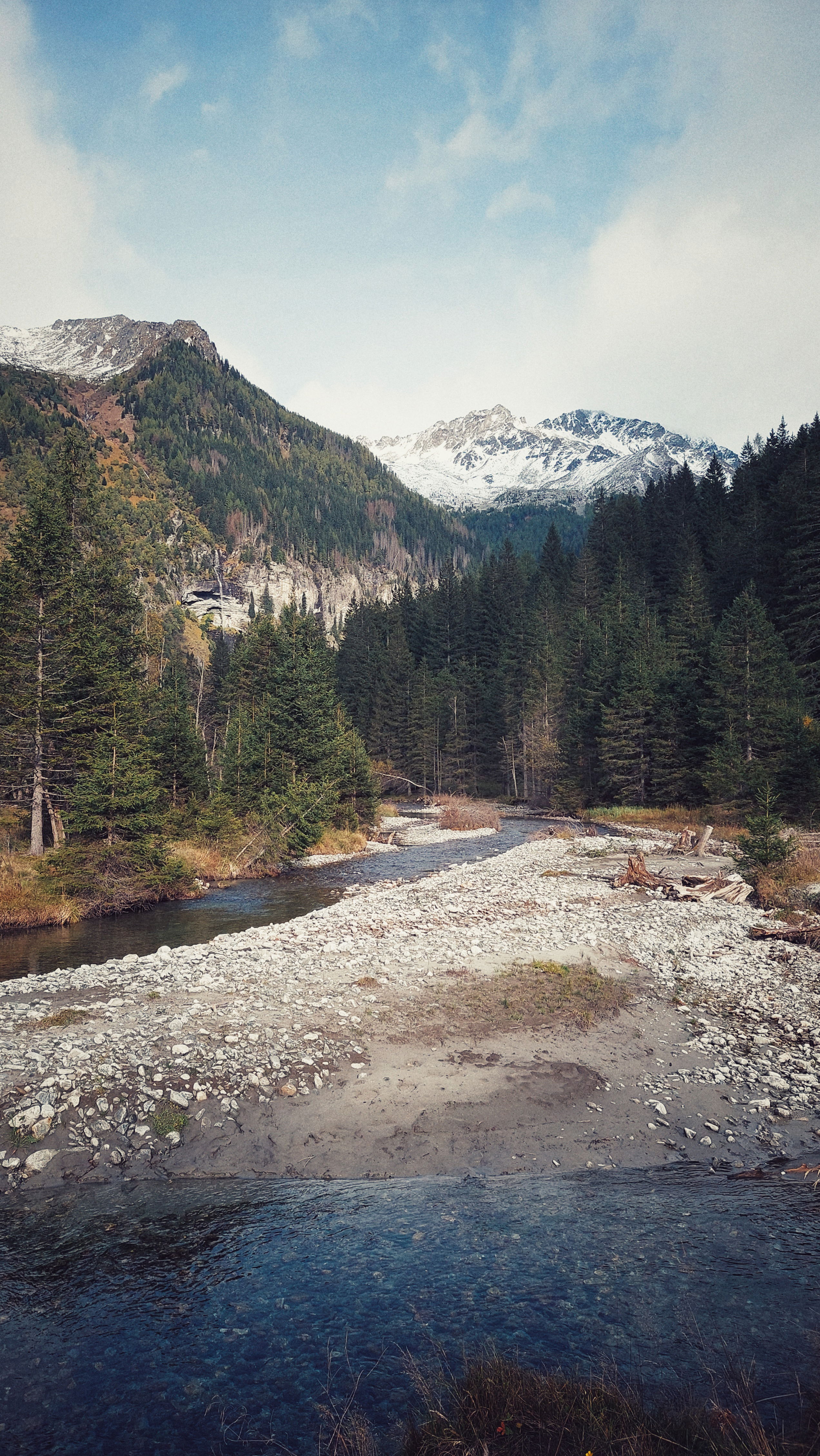 Snow covered mountains at the end of a wide river valley.