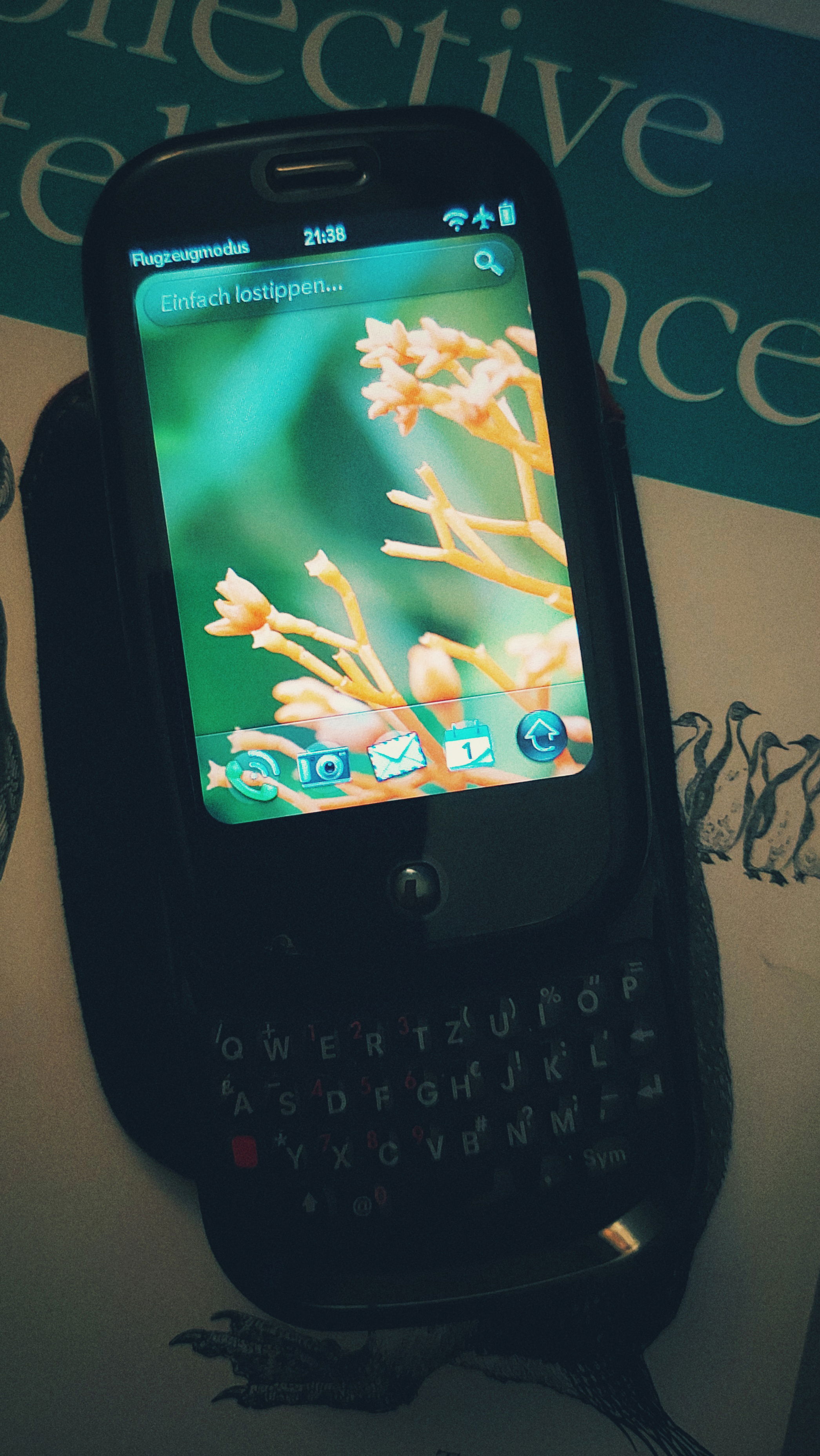 A Palm Pre I, keyboard lid opened, default background and screen layout, on a copy of O'Reilly Programming Collective Intelligence. Memories.