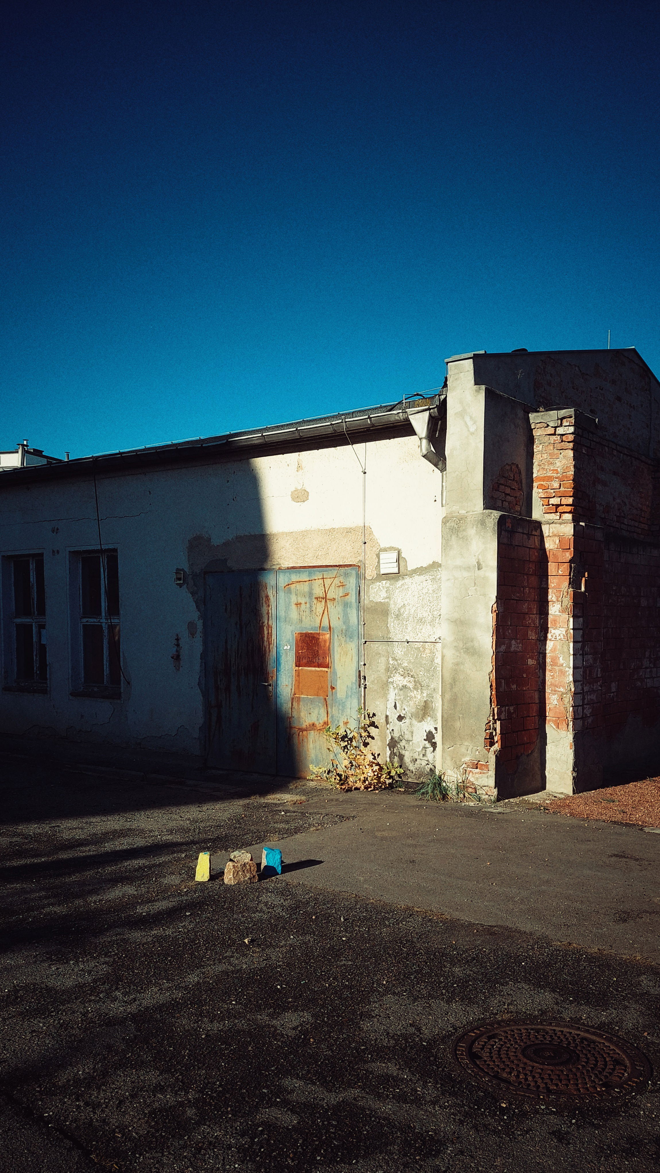Quiet blue sky above an old workshop building. 