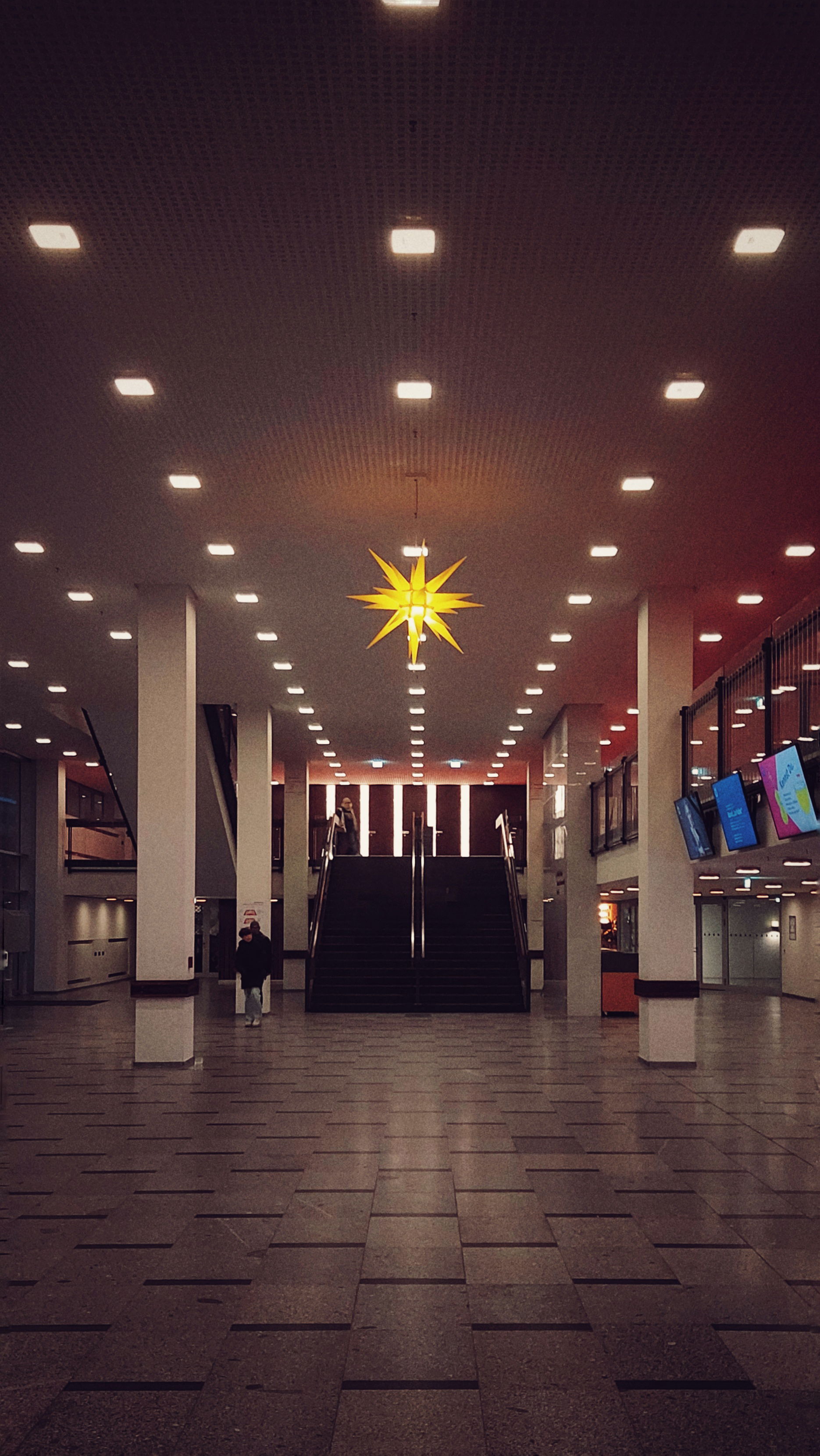 Stairs and a modern hallway, illuminated by ceiling lights. And a single Christmas star right in the middle.