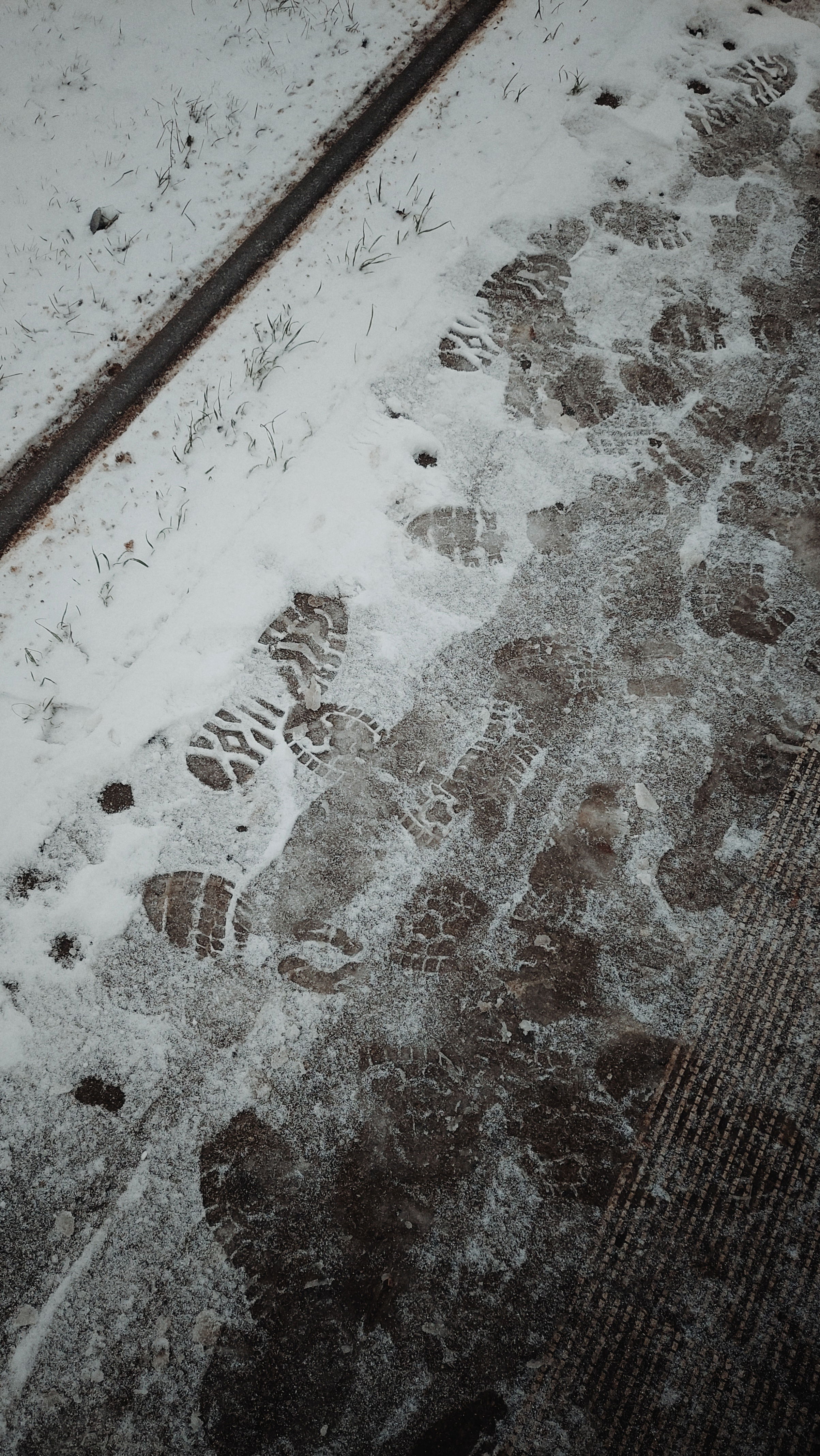 A tram platform covered by light snow and a lot of darker footprints, some rather clearly outlined, some already fuzzy and vague. 