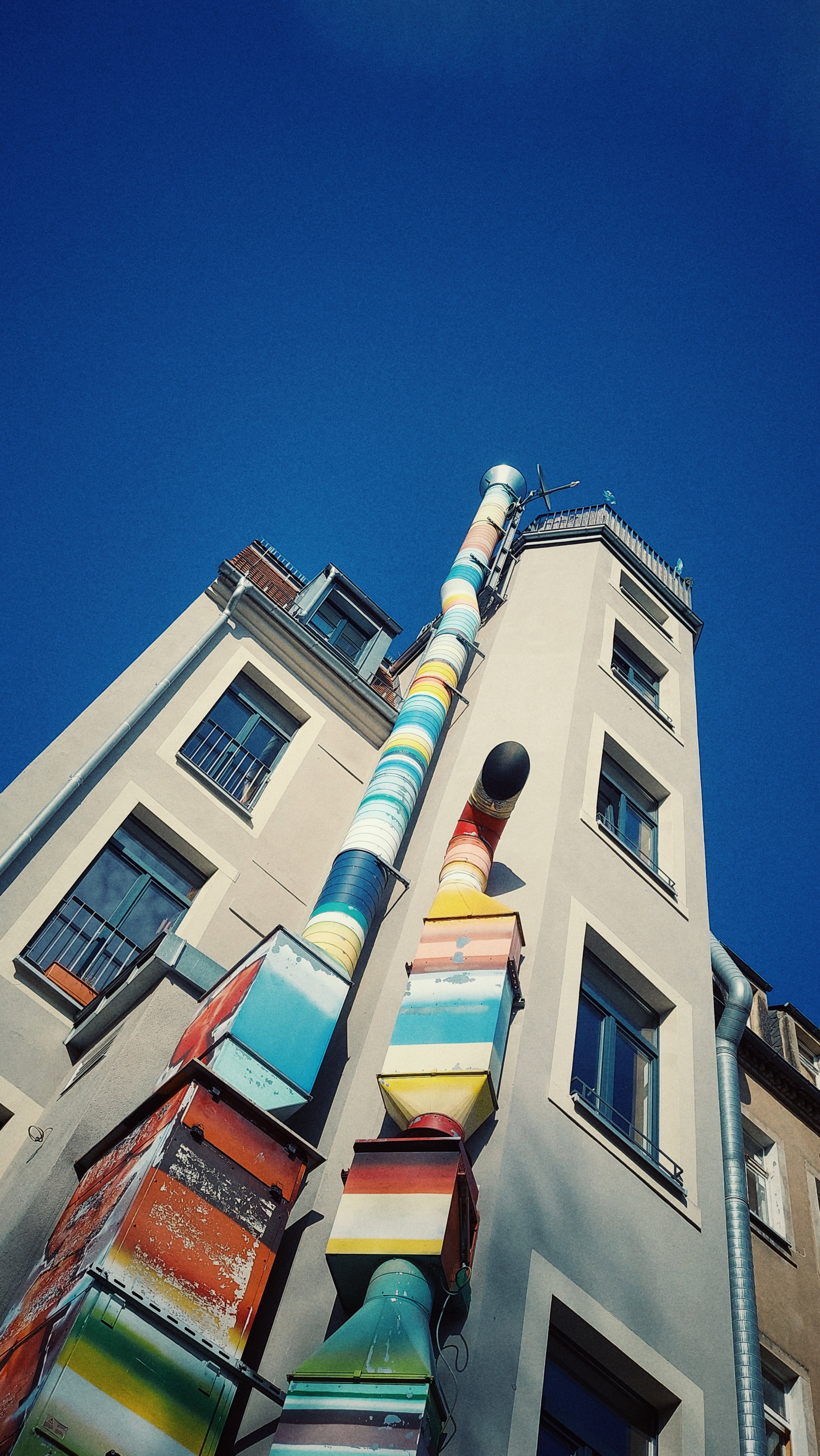 Looking up an old house and a brightly coloured pipe.