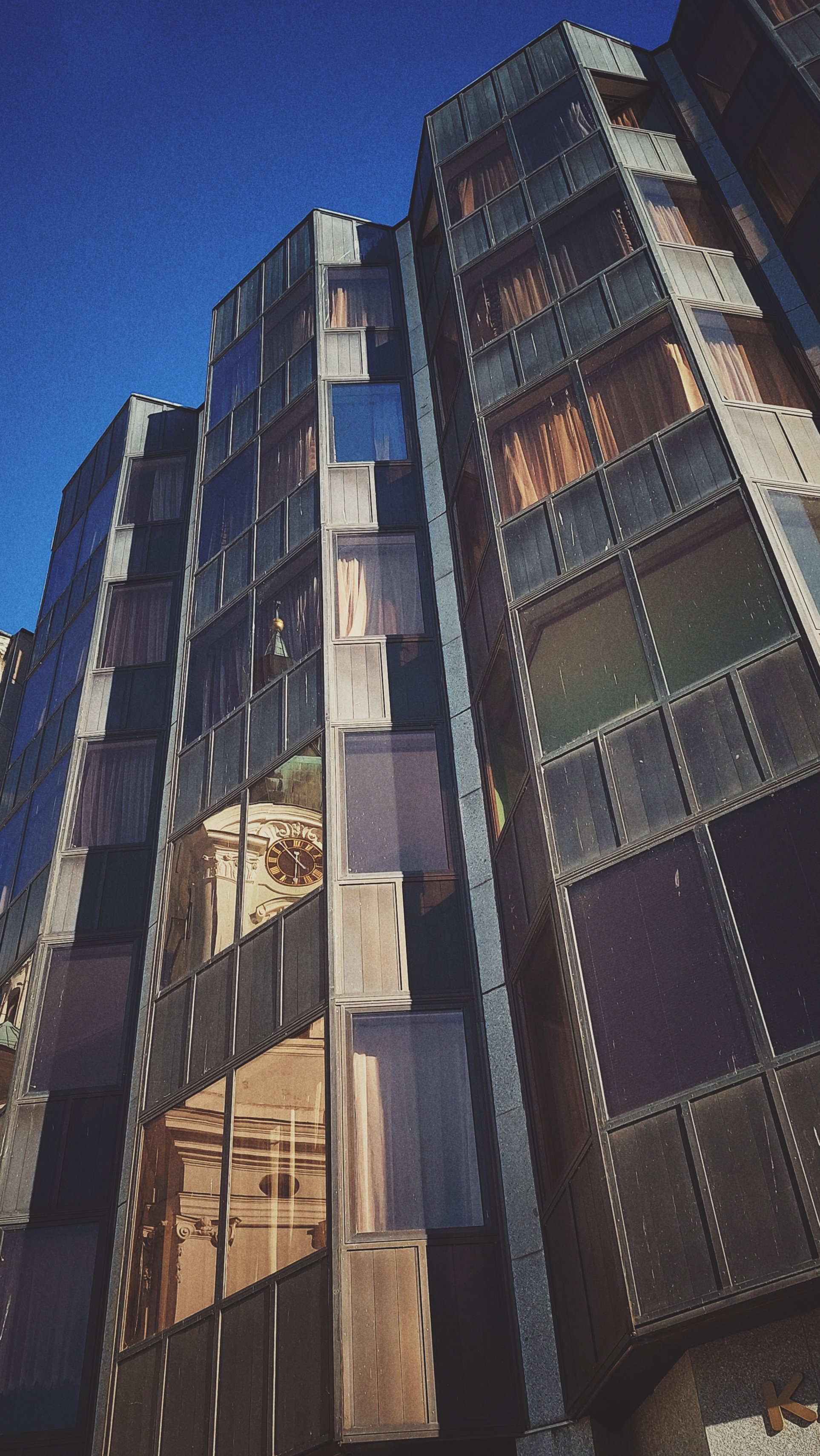 An old belfry reflected by a glass facade. 