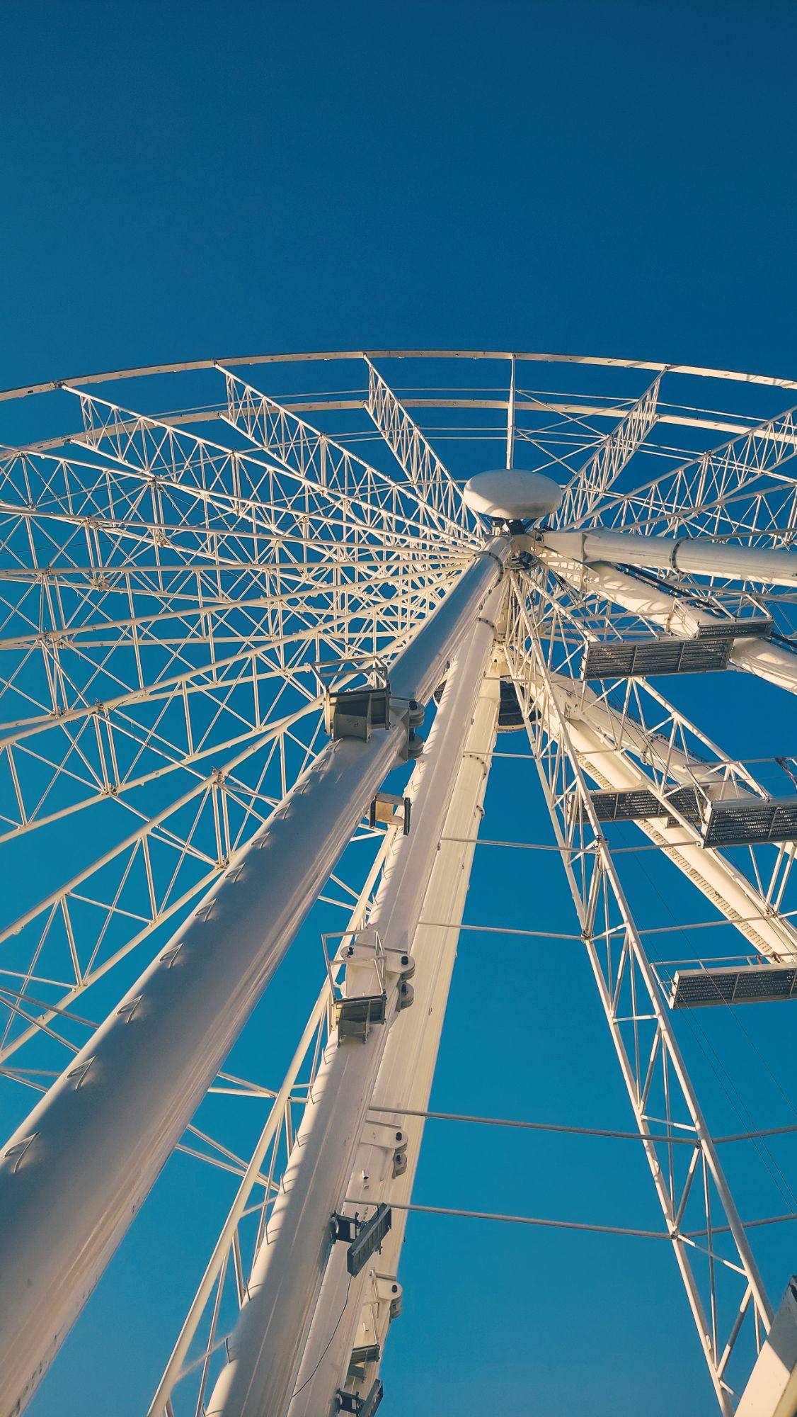 A huge white ferris wheel seen from below.