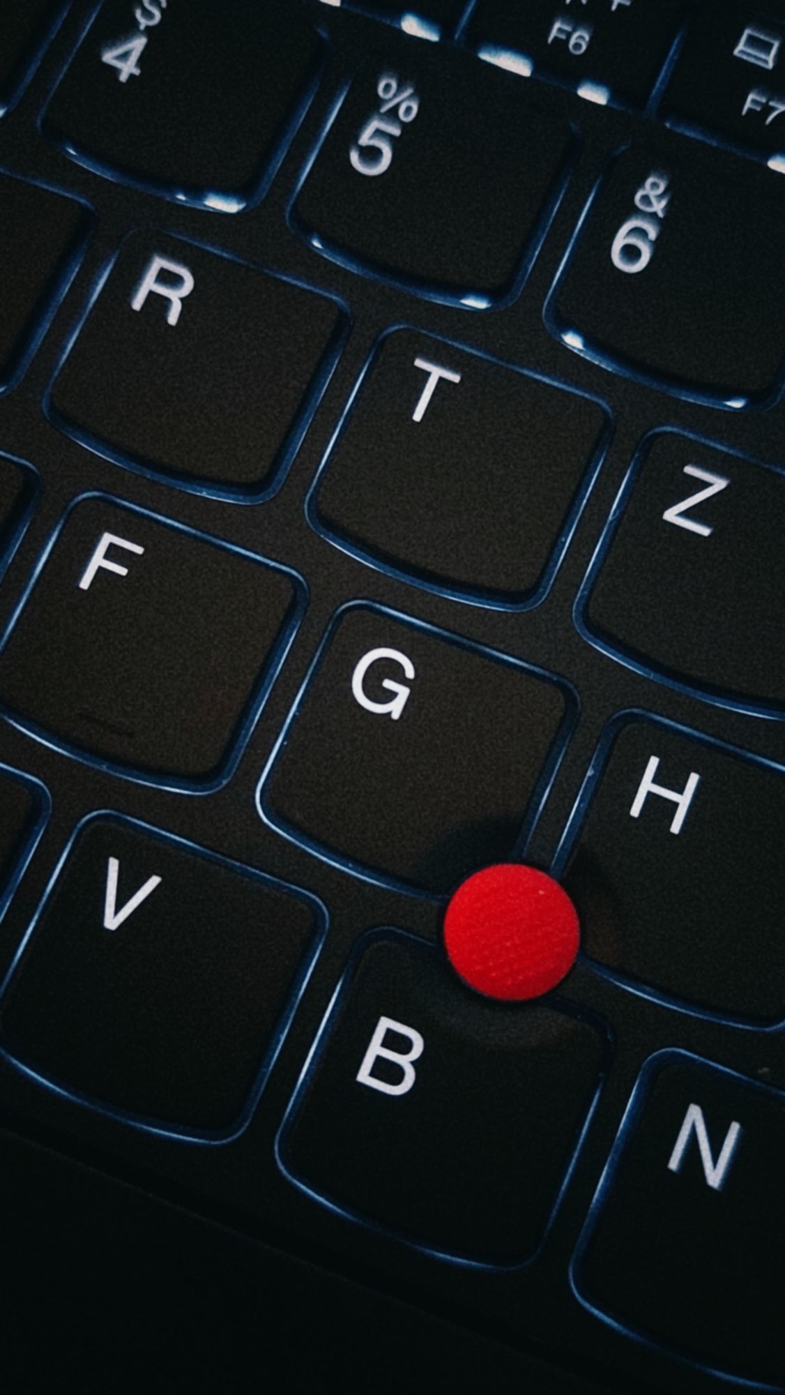Closeup of a laptop keyboard. A red dot in between.