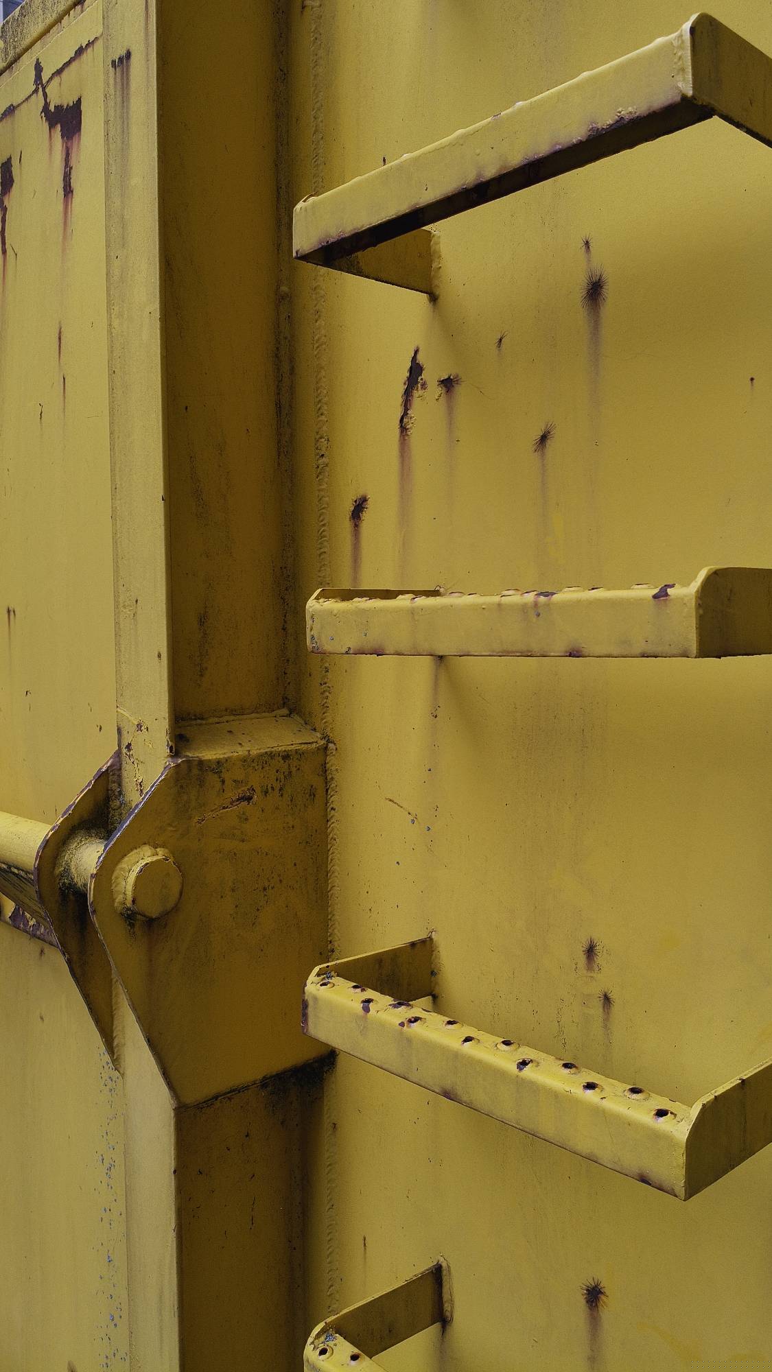 Yellow iron ladder steps on a construction site container.