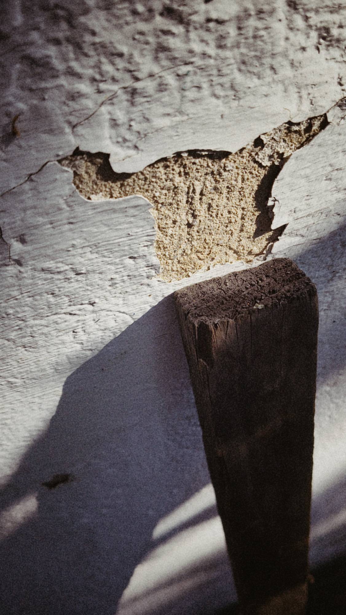 A wooden pole and a slightly defective wall.