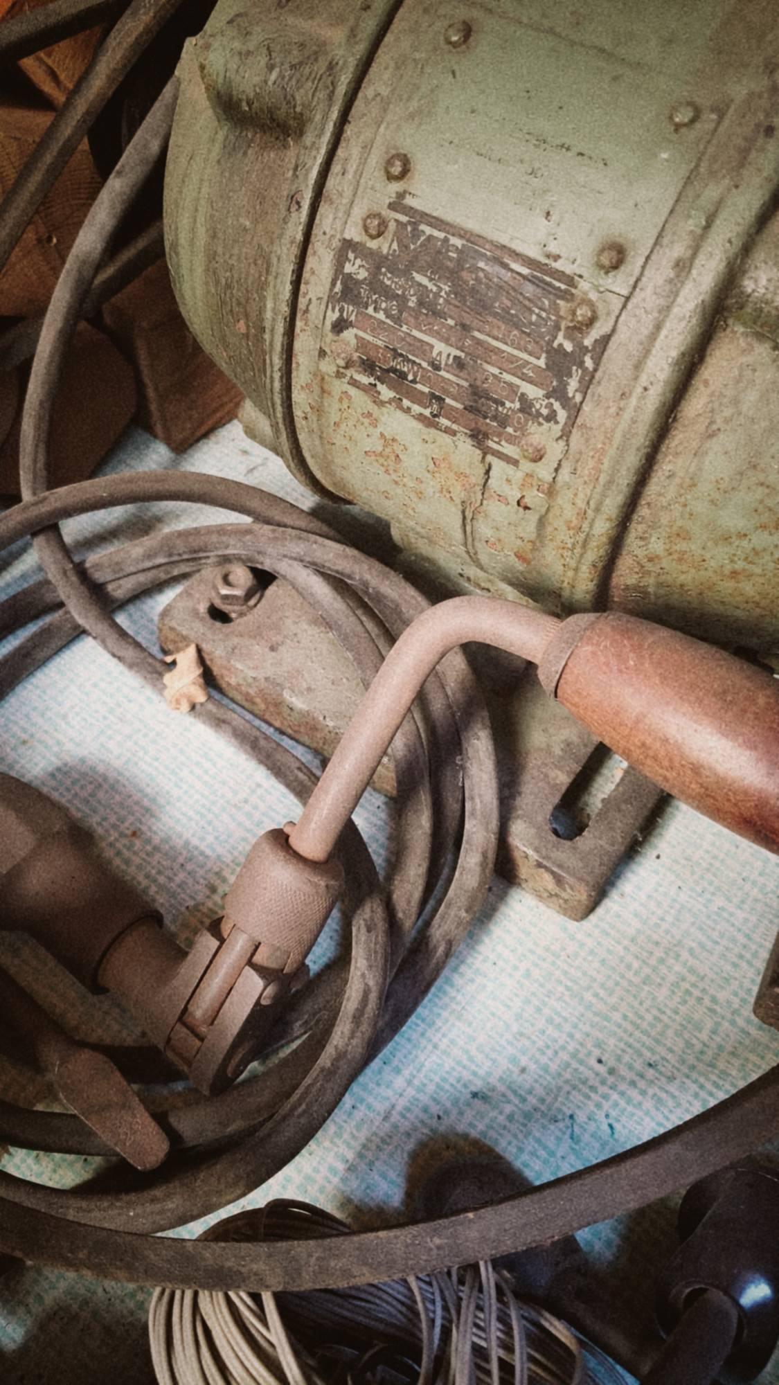 An old engine and part of a manual drill on a table.