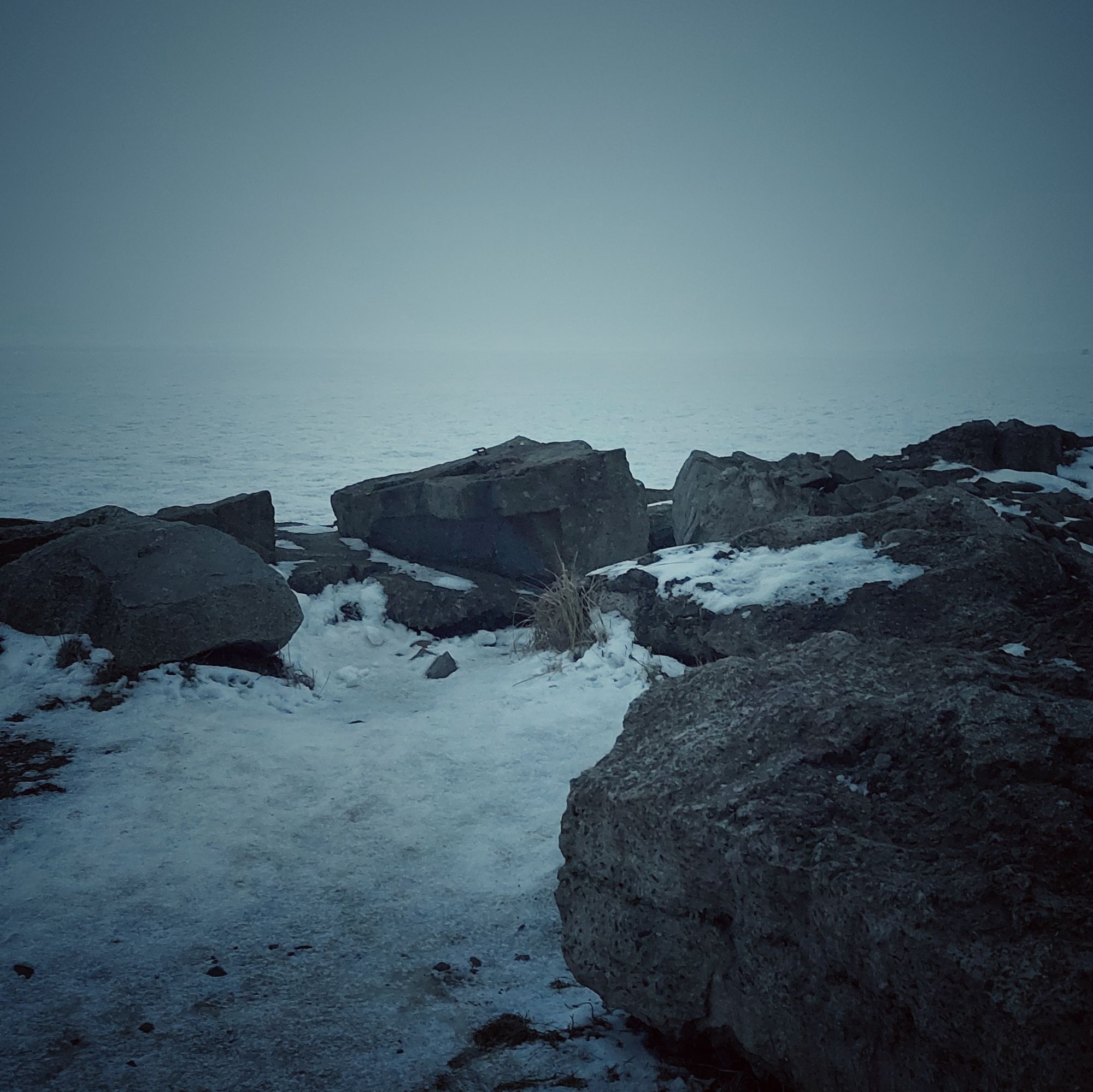Rocks in snow, the frozen sea behind.
