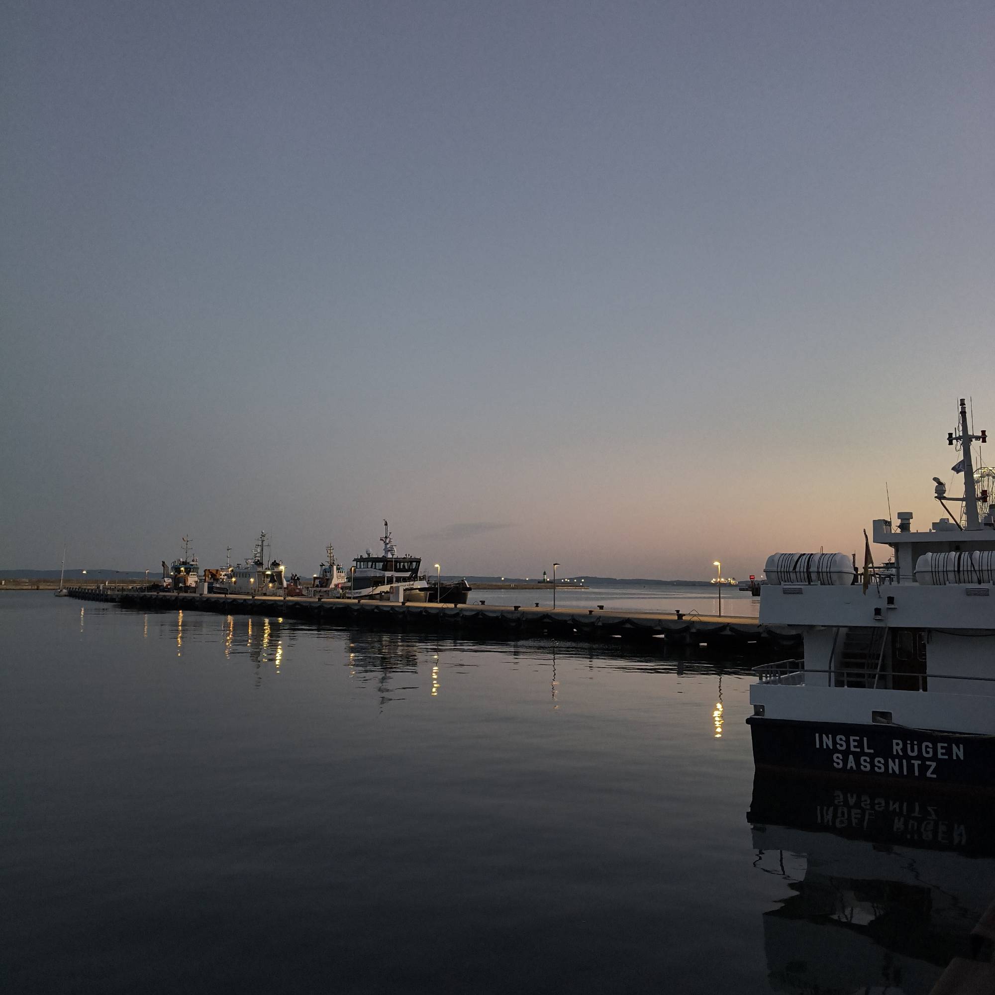 A ship on a quay resting on a calm sea. Late sunset light.
