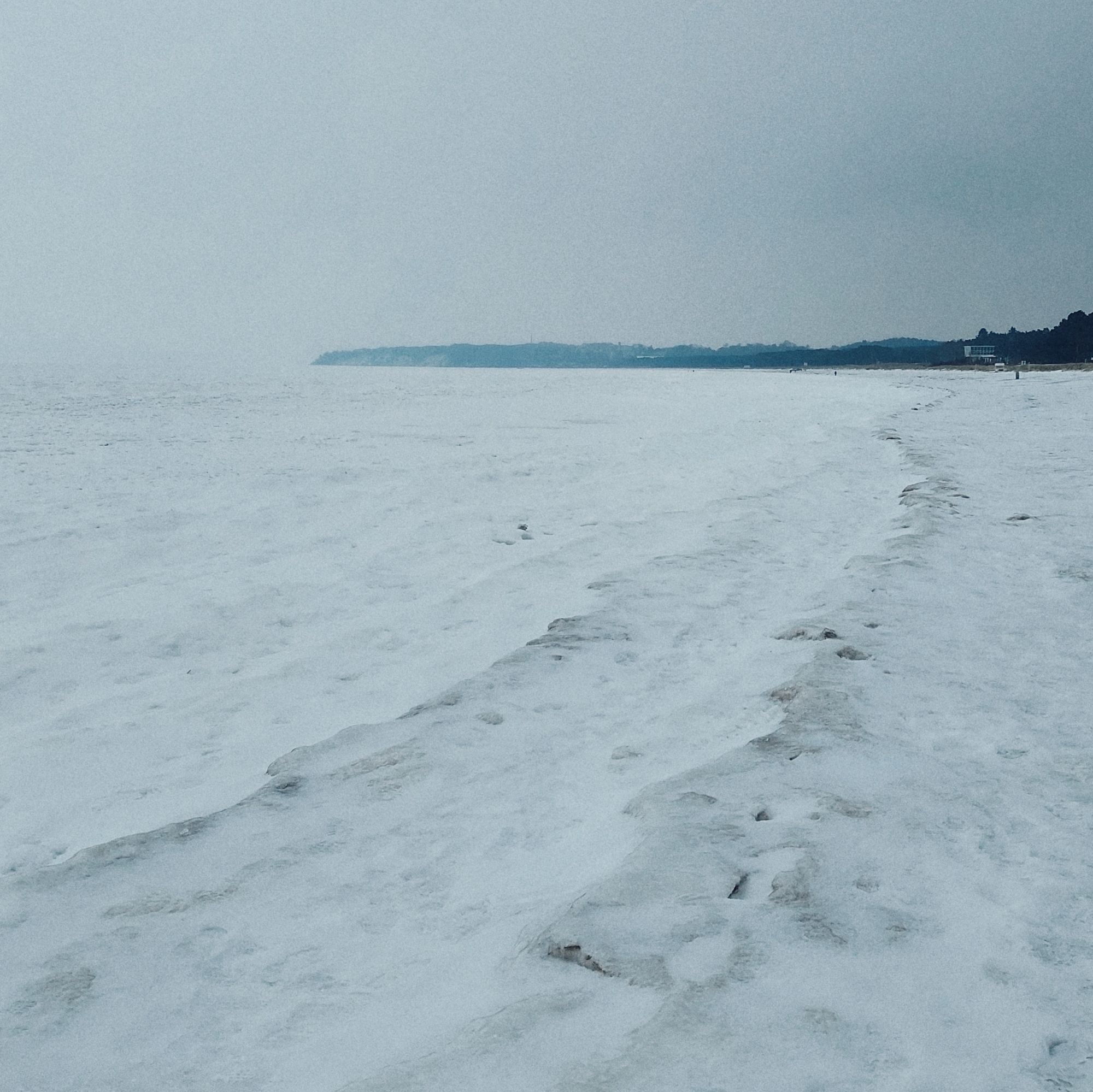 Frozen waves and a steep coast in the distance.